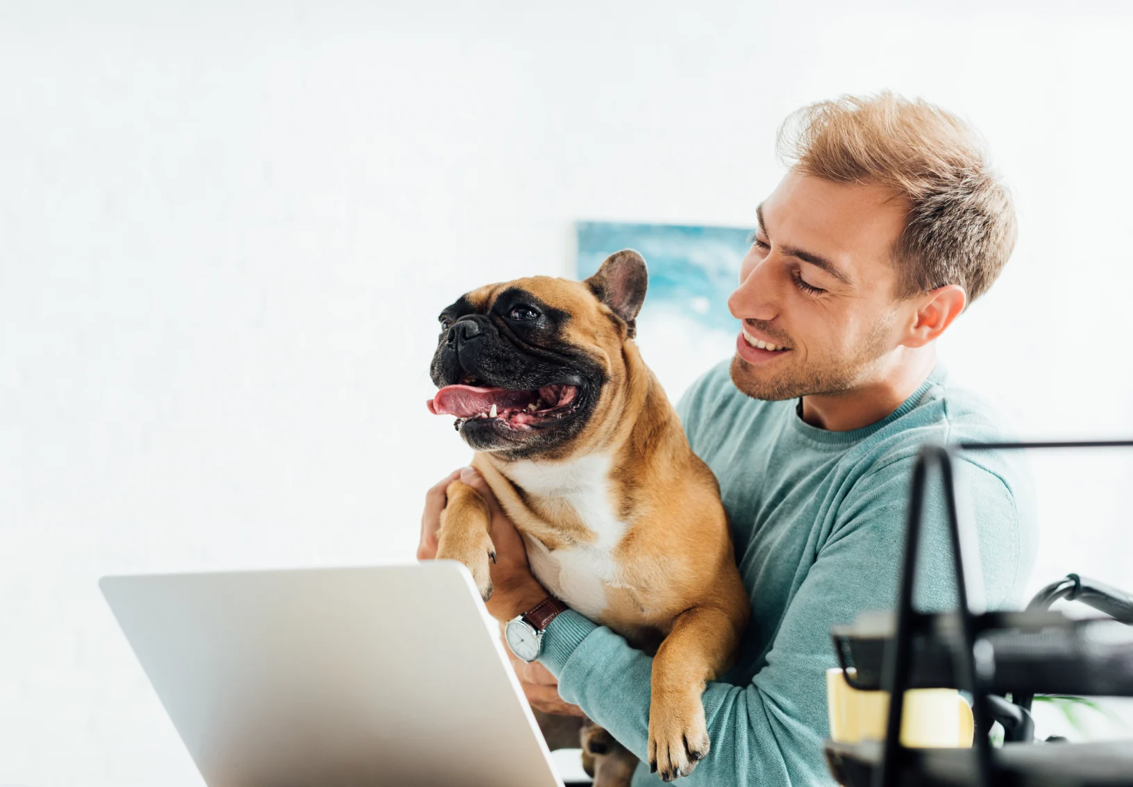 Man holding dog up in front of laptop